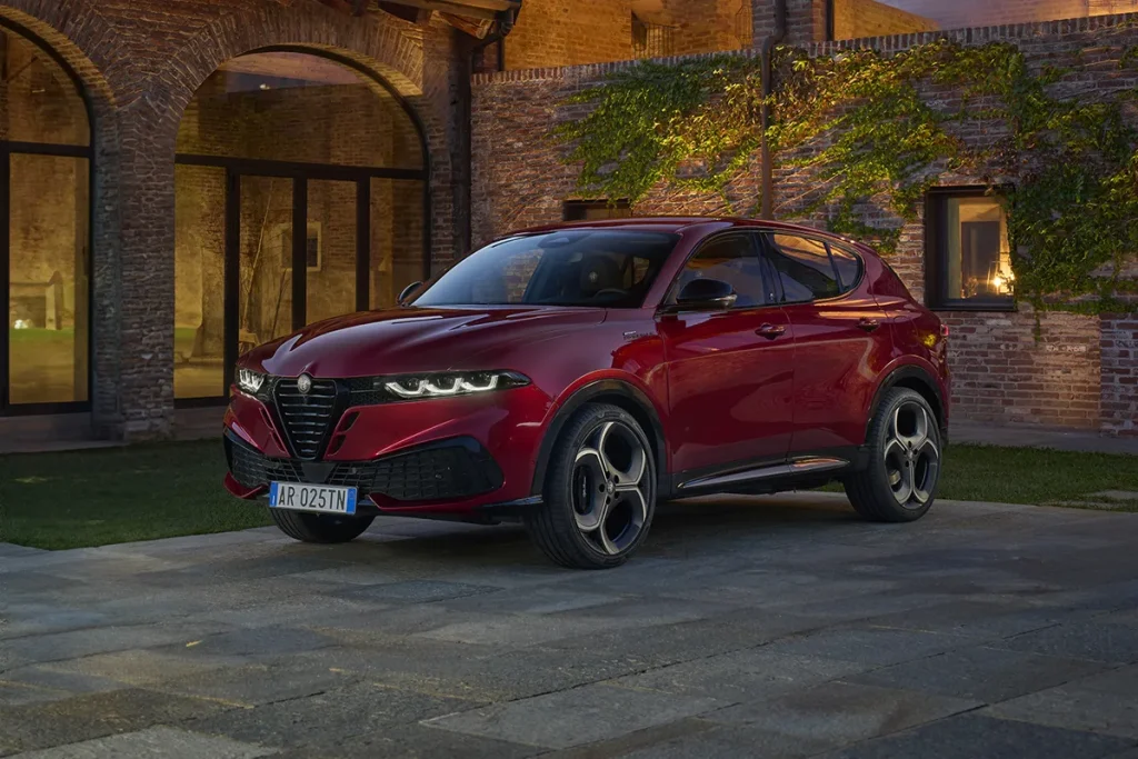Alfa Romeo Tonale Rossa parcheggiata davanti una casa moderna con mattoni a vista