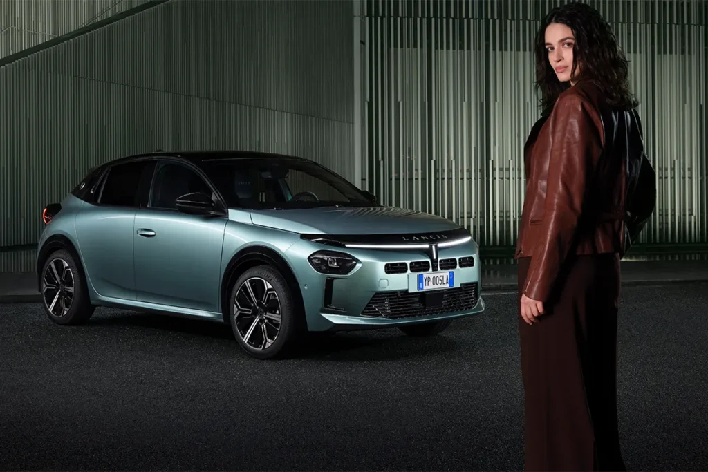 lancia ypsilon azzurra parcheggiata con ragazza in primo piano